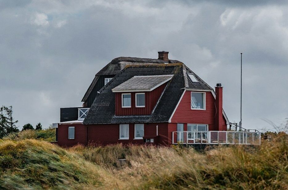 brown and black house near green grass field under white clouds during daytime